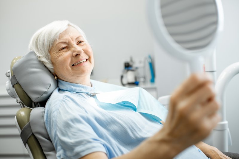 Older woman admiring her smile with dental implants in Bellingham.