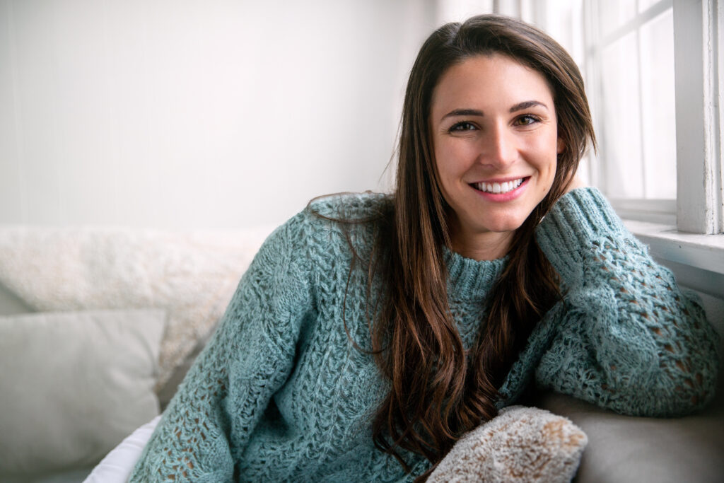 Woman in sweater sitting in chair and showing off her bright smile