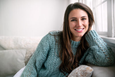 Woman in sweater sitting in chair and showing off her bright smile.